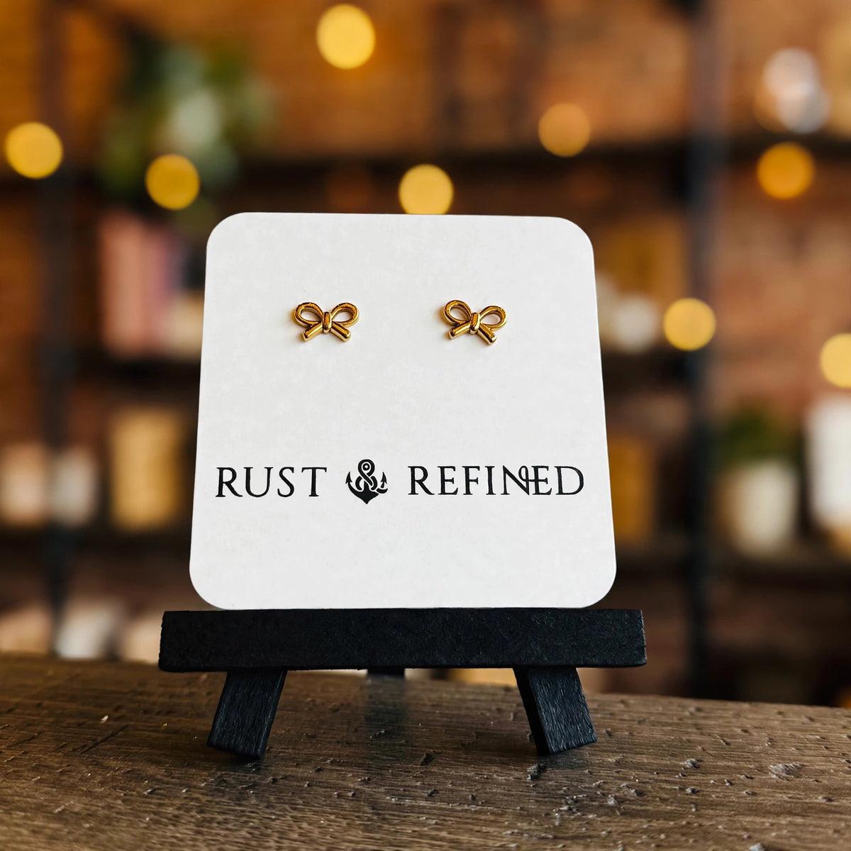 Gold bow stud earrings on a Rust & Refined card
