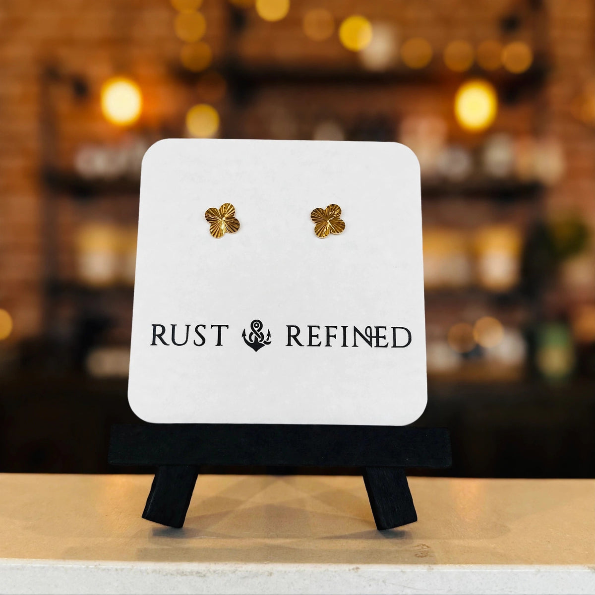 Gold flower stud earrings on a Rust & Refined card