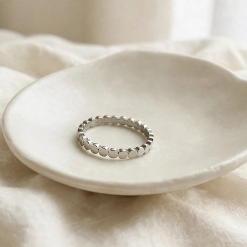 Flat Circle Stacking Ring in polished stainless steel on a ceramic dish