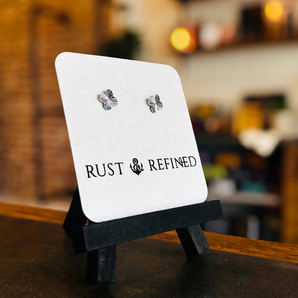 Silver flower stud earrings on a Rust & Refined card, angled view