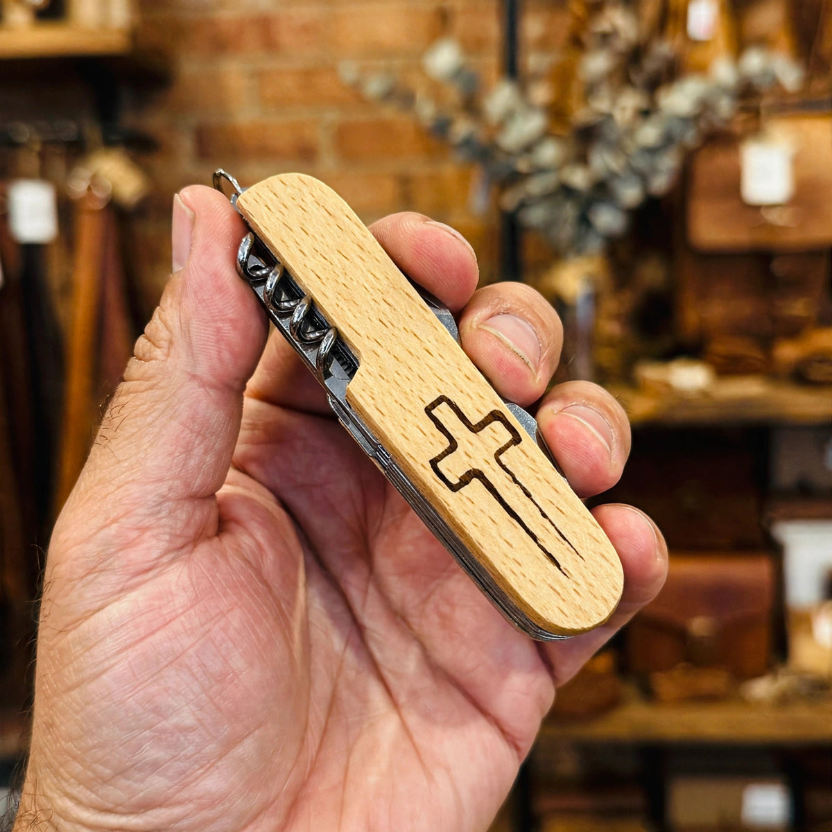 Cross Engraved Pocket Knife held in hand for scale