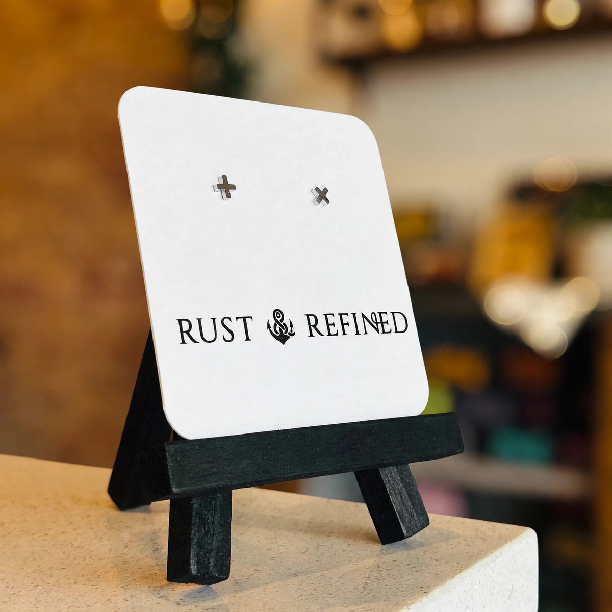 Silver plus and X stud earrings on a Rust & Refined card, angled view