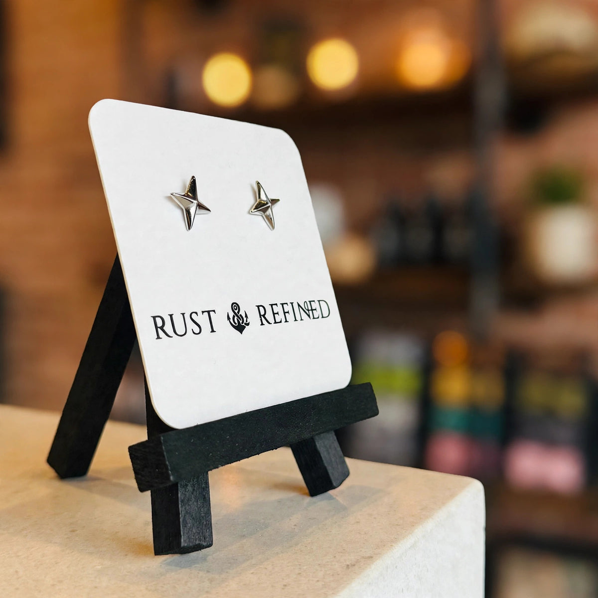 Silver star stud earrings on a Rust & Refined card, angled view