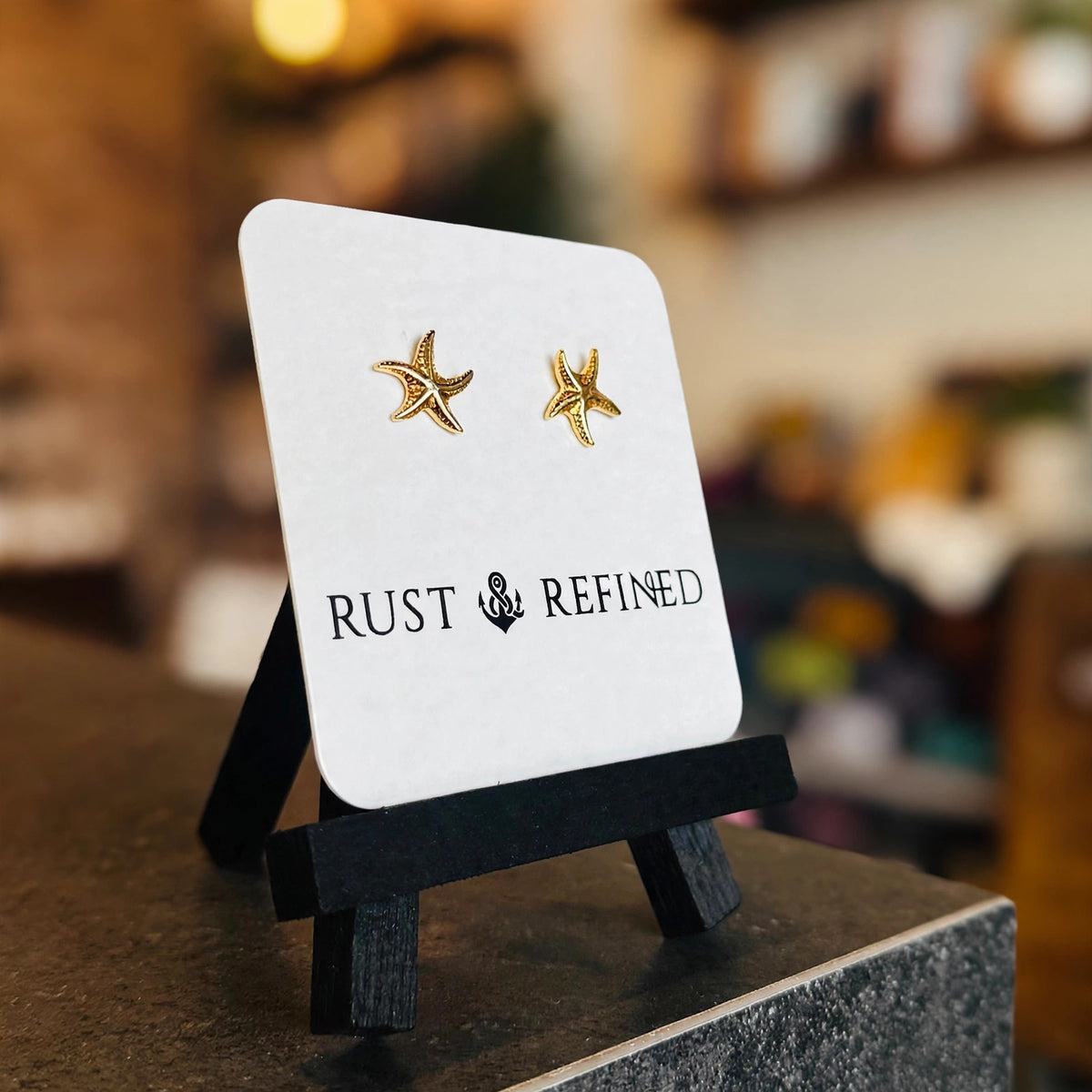 Gold starfish stud earrings on a Rust & Refined card, angled view