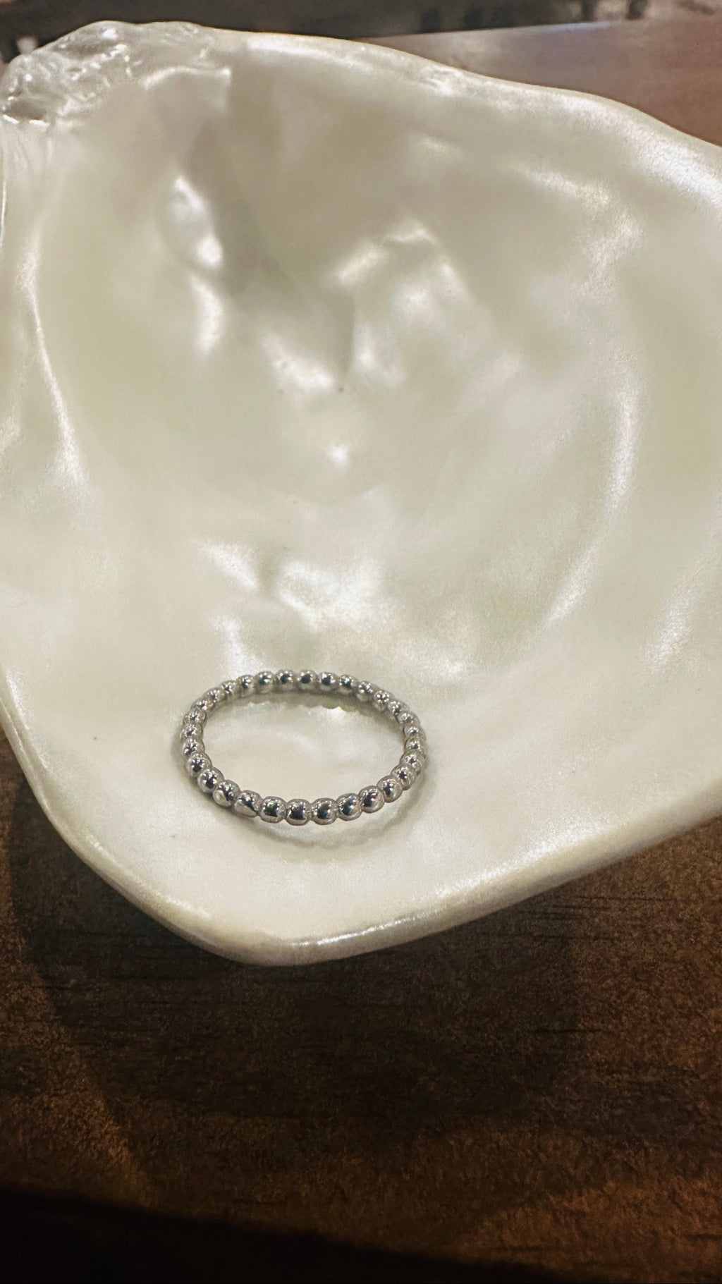 Beaded Spacer Ring in polished stainless steel on a shell dish