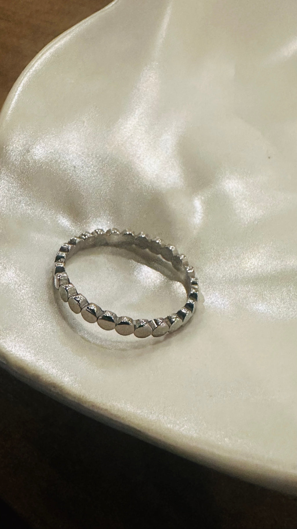 Flat Circle Stacking Ring in polished stainless steel on a shell dish