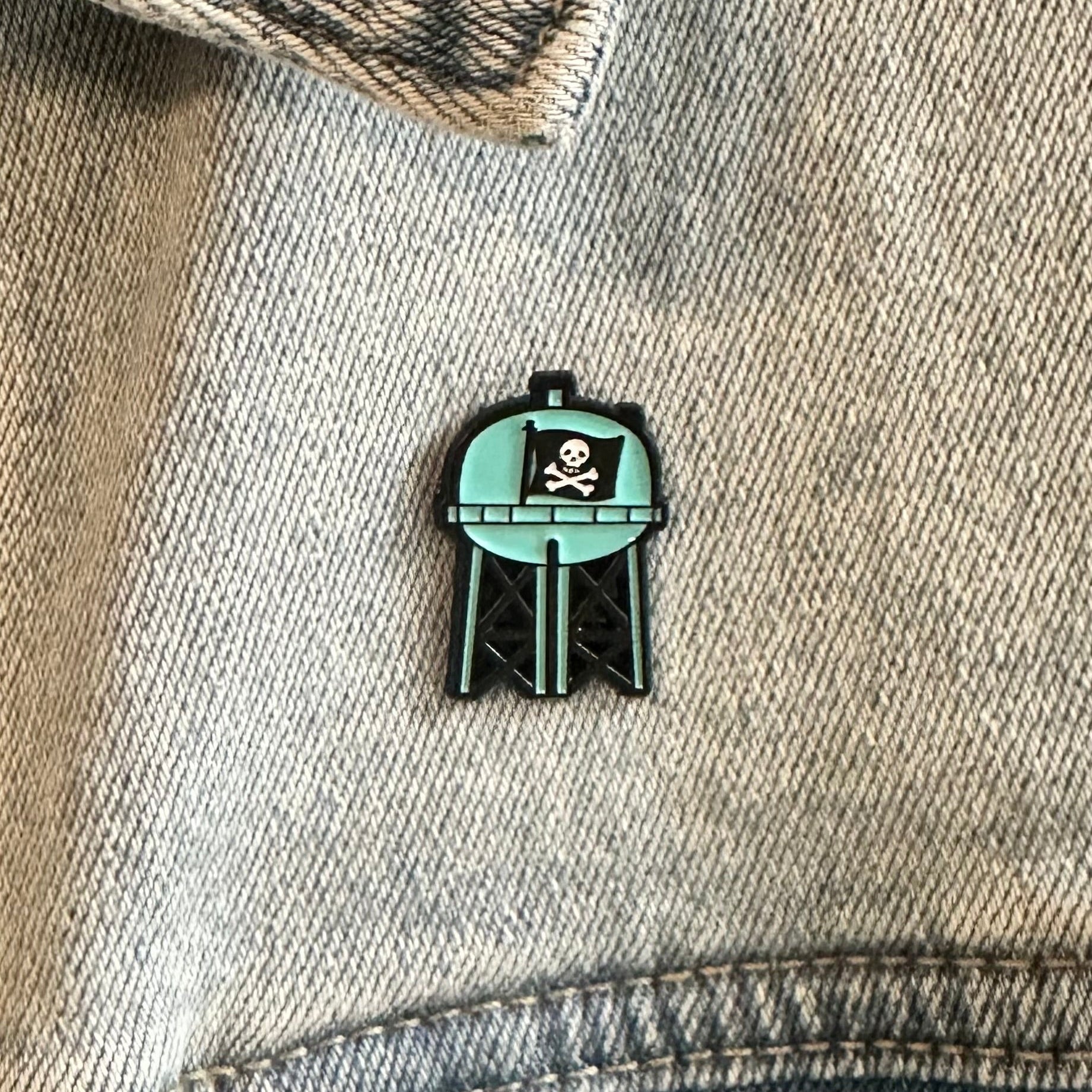 Pin on a denim jacket with a skull and crossbones design.