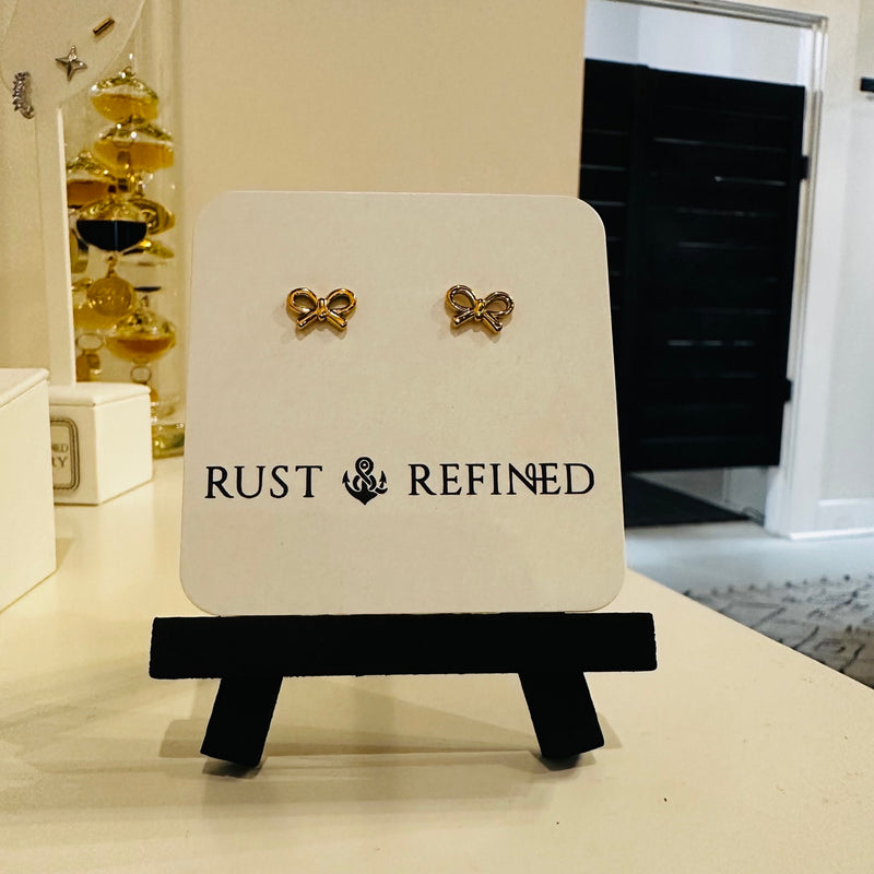 Gold bow stud earrings on Rust and Refined card