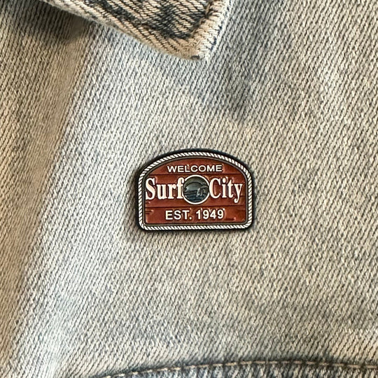 Denim jacket with 'Welcome to Surf City' patch on a close-up of fabric.