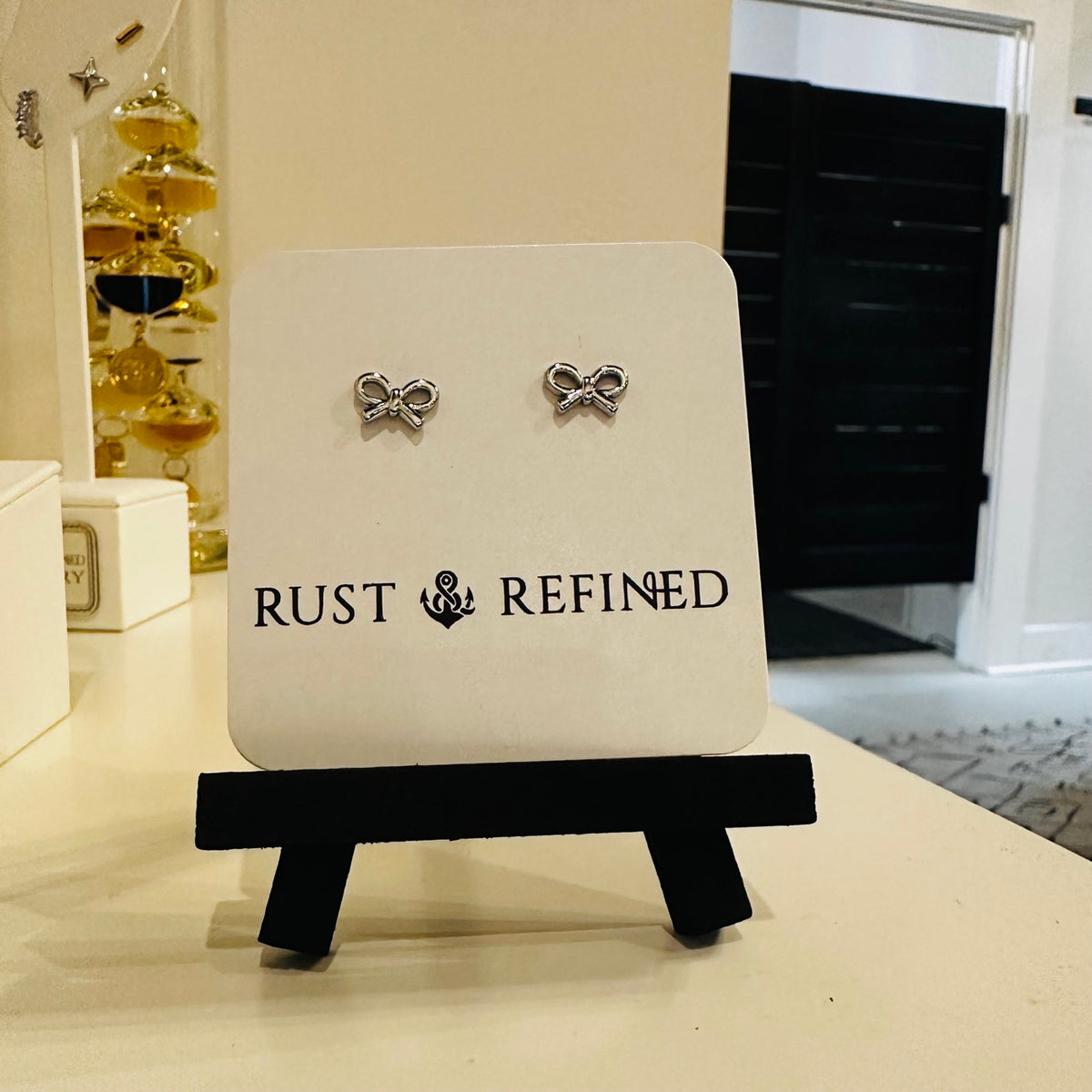 Silver bow stud earrings on Rust and Refined card