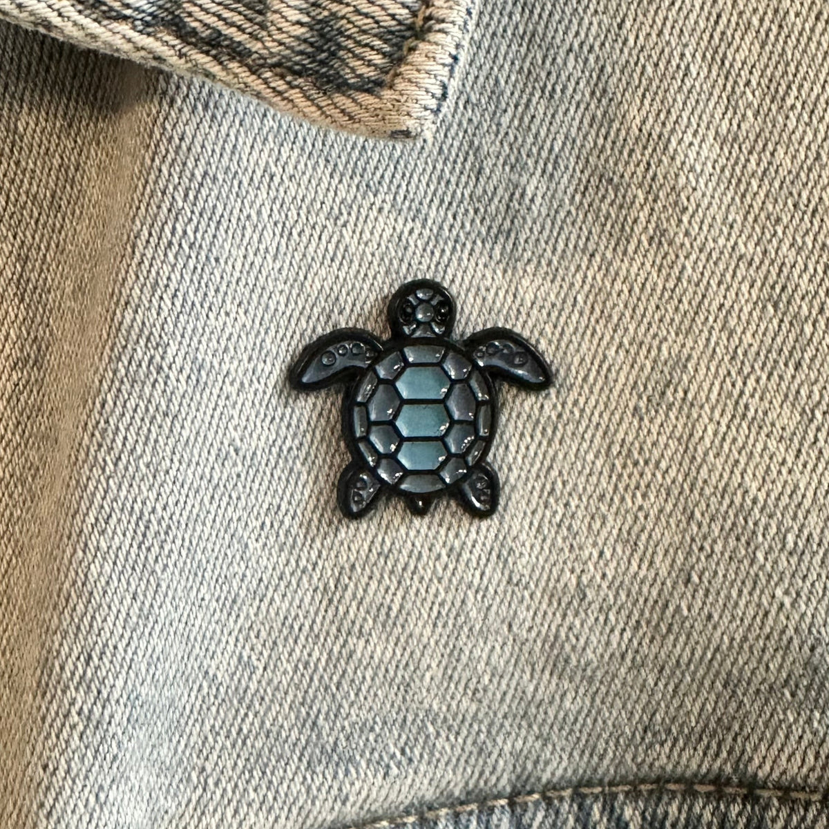 Black turtle-shaped pin on a denim jacket