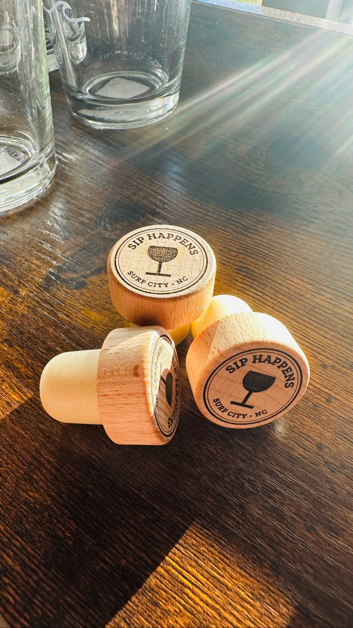 Sip Happens Wine Stopper, engraved wood stoppers on a dark wood counter