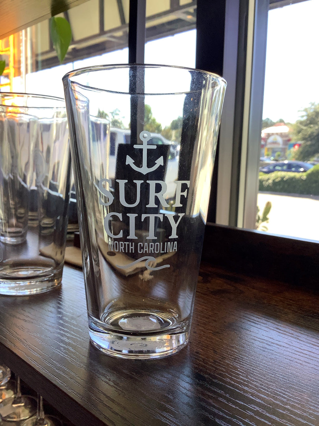Surf City Anchor pint glass on the store shelf by the window
