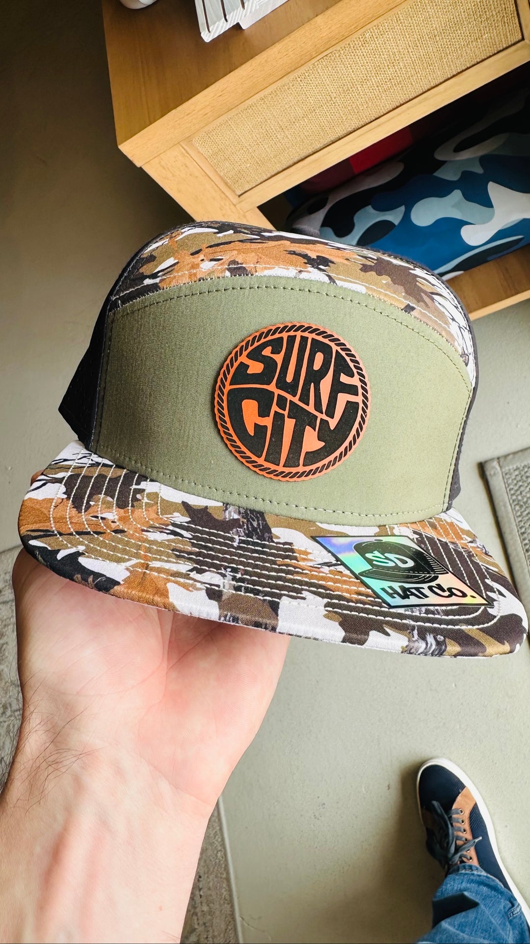 Olive green and white camo trucker hat with Surf City leather circle patch