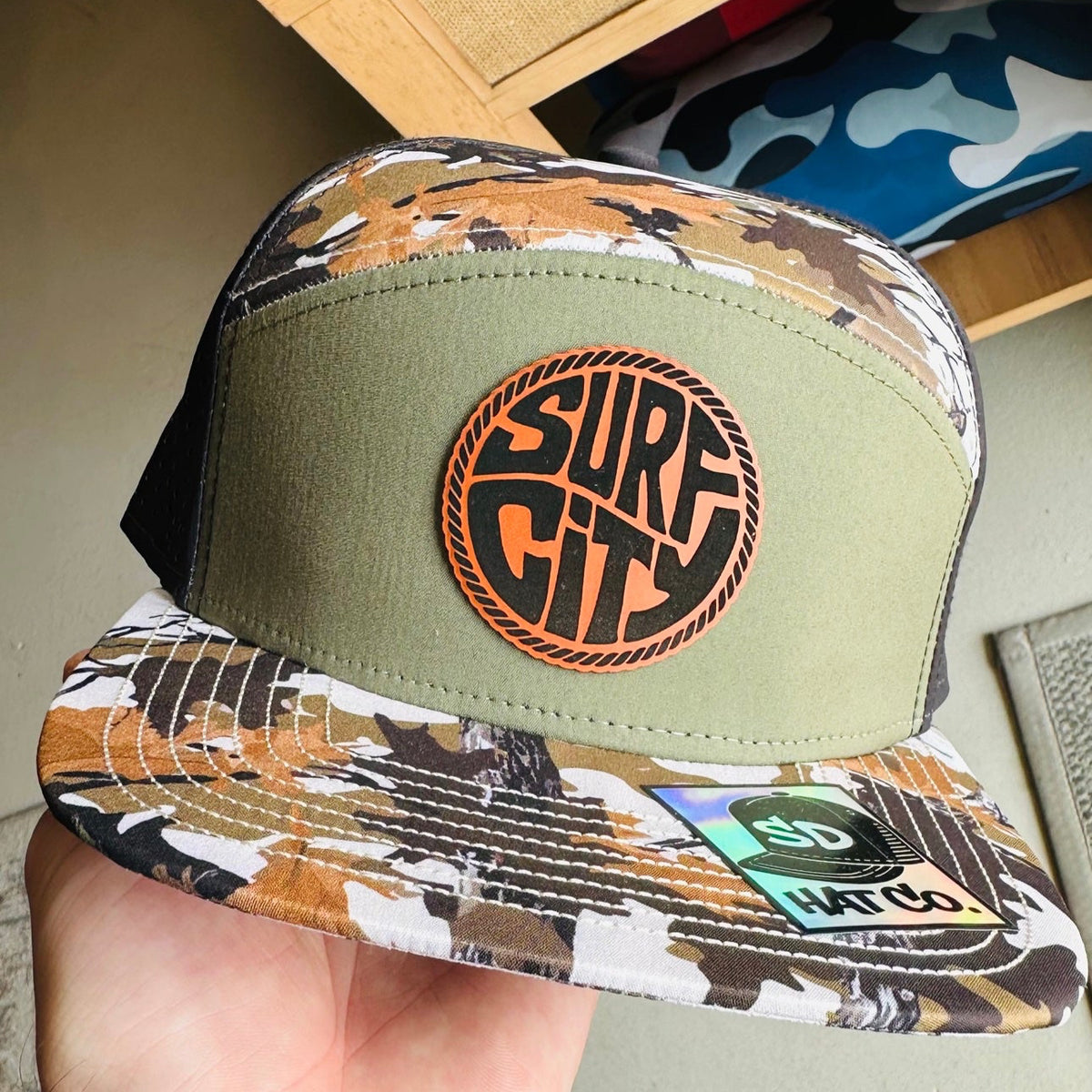 Olive green and white camo trucker hat with Surf City leather circle patch